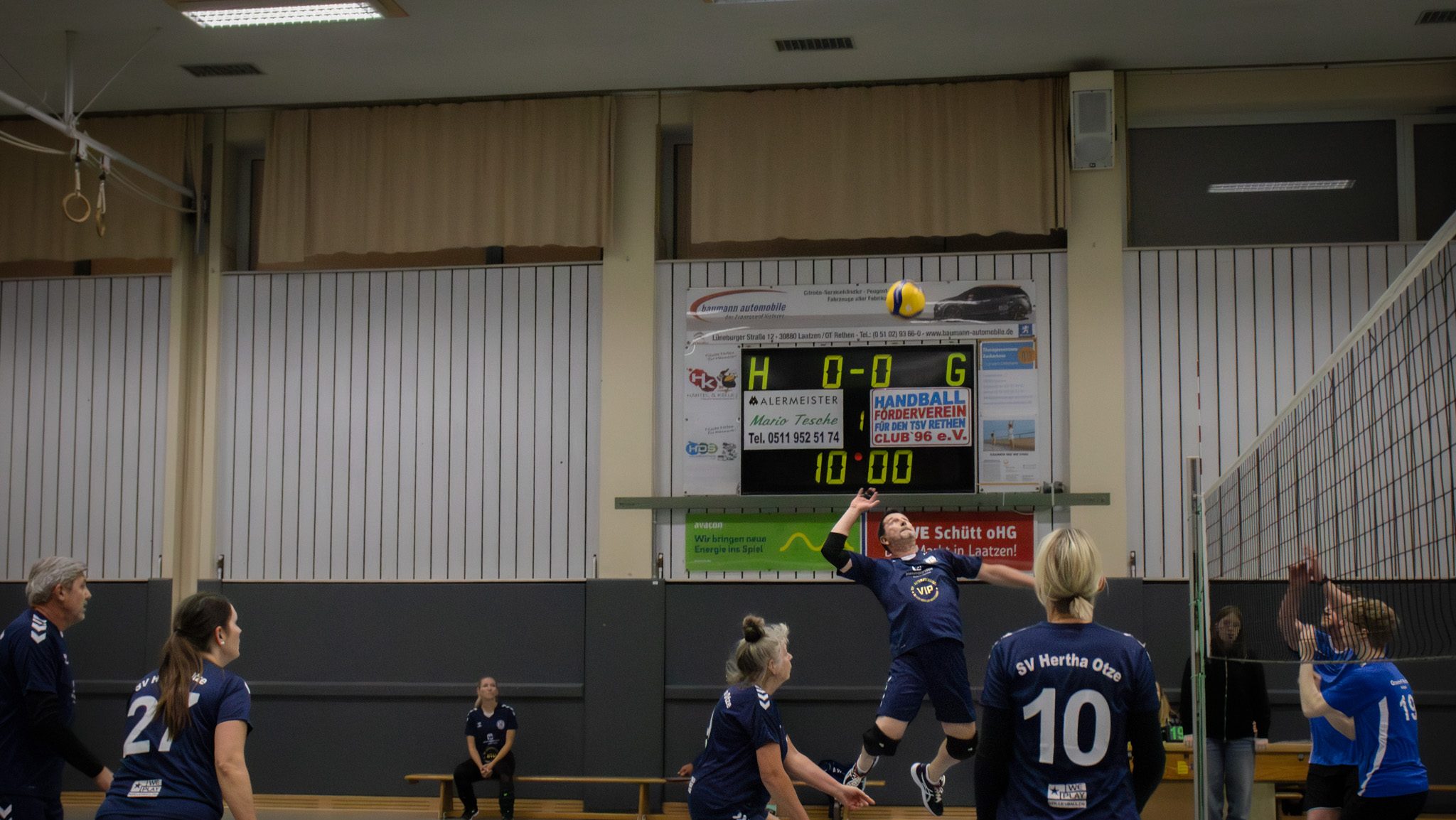Volleyballspiel in der Halle – ein Spieler des SV Hertha Otze springt zum Angriff über das Netz, während das gegnerische Team in Abwehrposition ist.