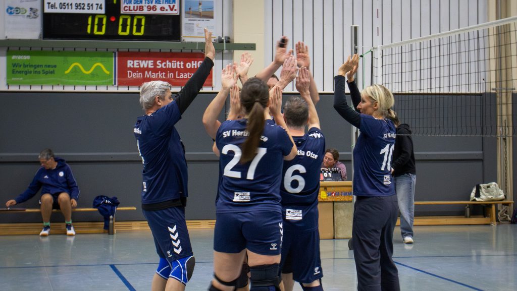 Volleyballspielende des SV Hertha Otze im Trikot bilden einen Kreis und geben sich gegenseitig ein motivierendes High-Five.