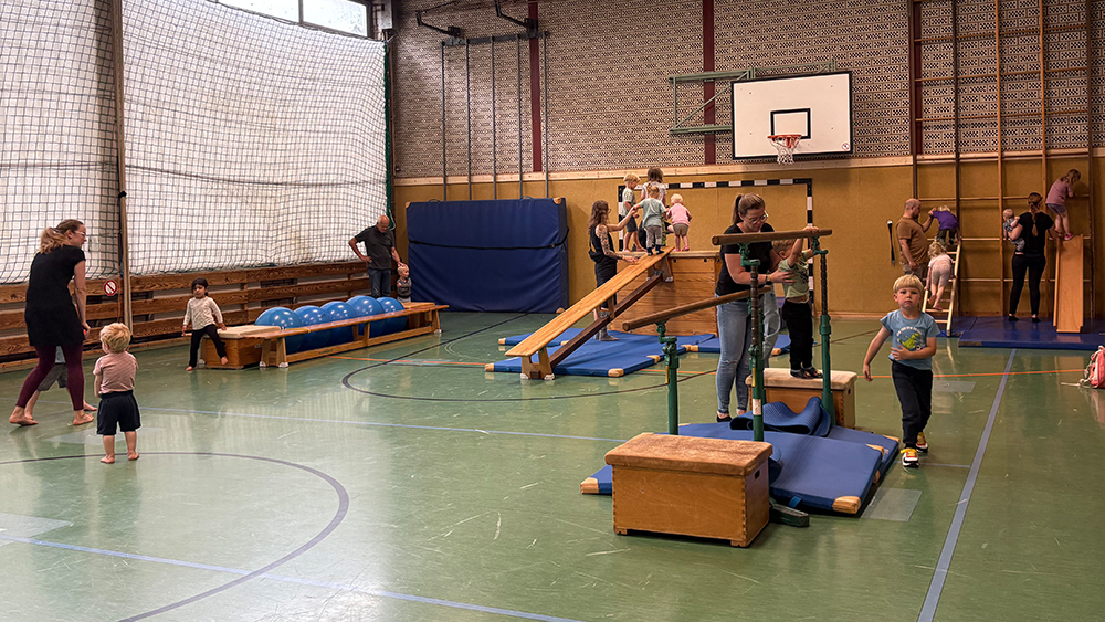 Bewegungslandschaft in der Turnhalle mit vielen Kindern auf Klettergeräten.