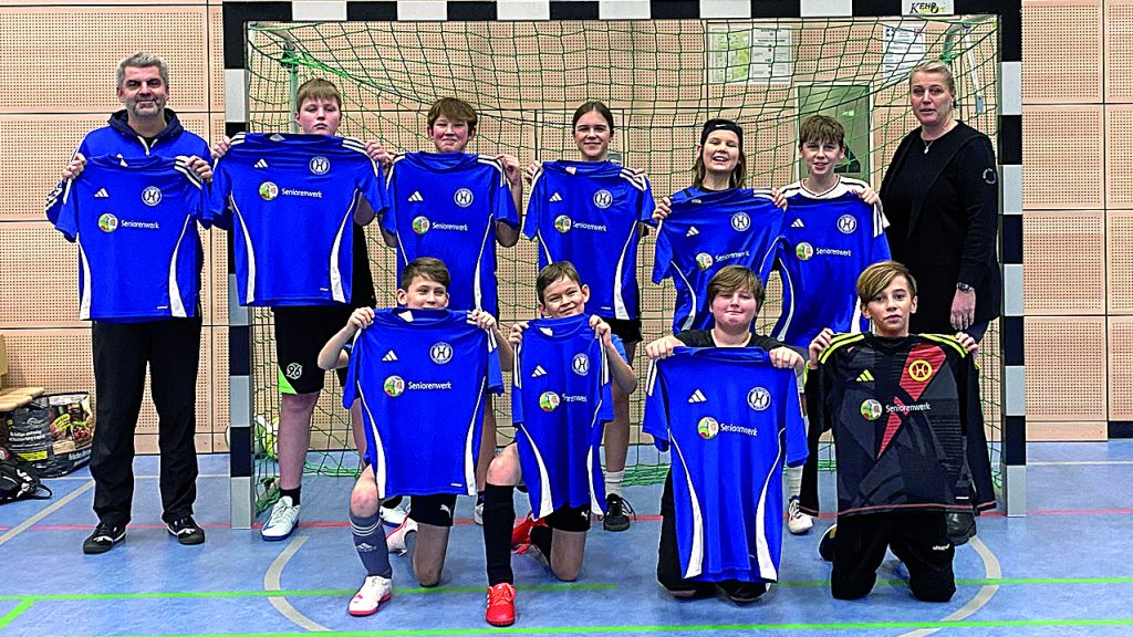 Jugendmannschaft des SV Hertha Otze präsentiert neue blaue Trikots mit Sponsorenlogo in einer Sporthalle.